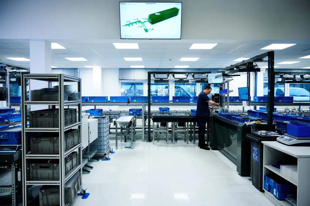 Automated warehouse workstation with conveyors, load carriers and operator